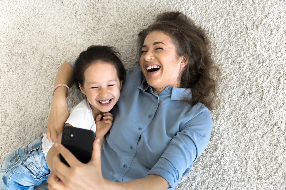 Mom and daughter hugging on carpet.