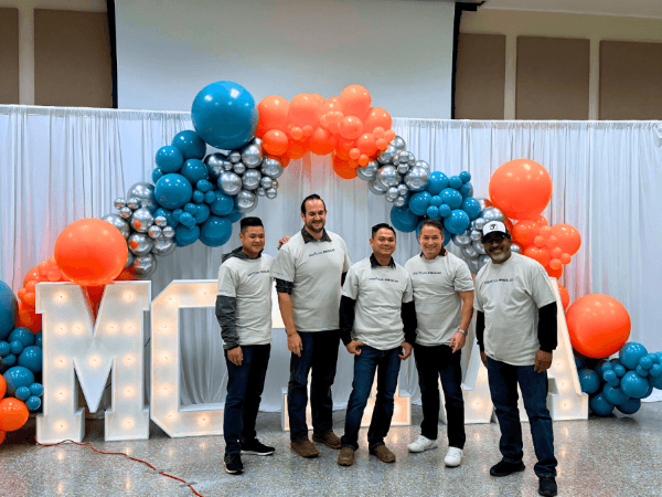 Five Motiva employees stand in front of balloon arch