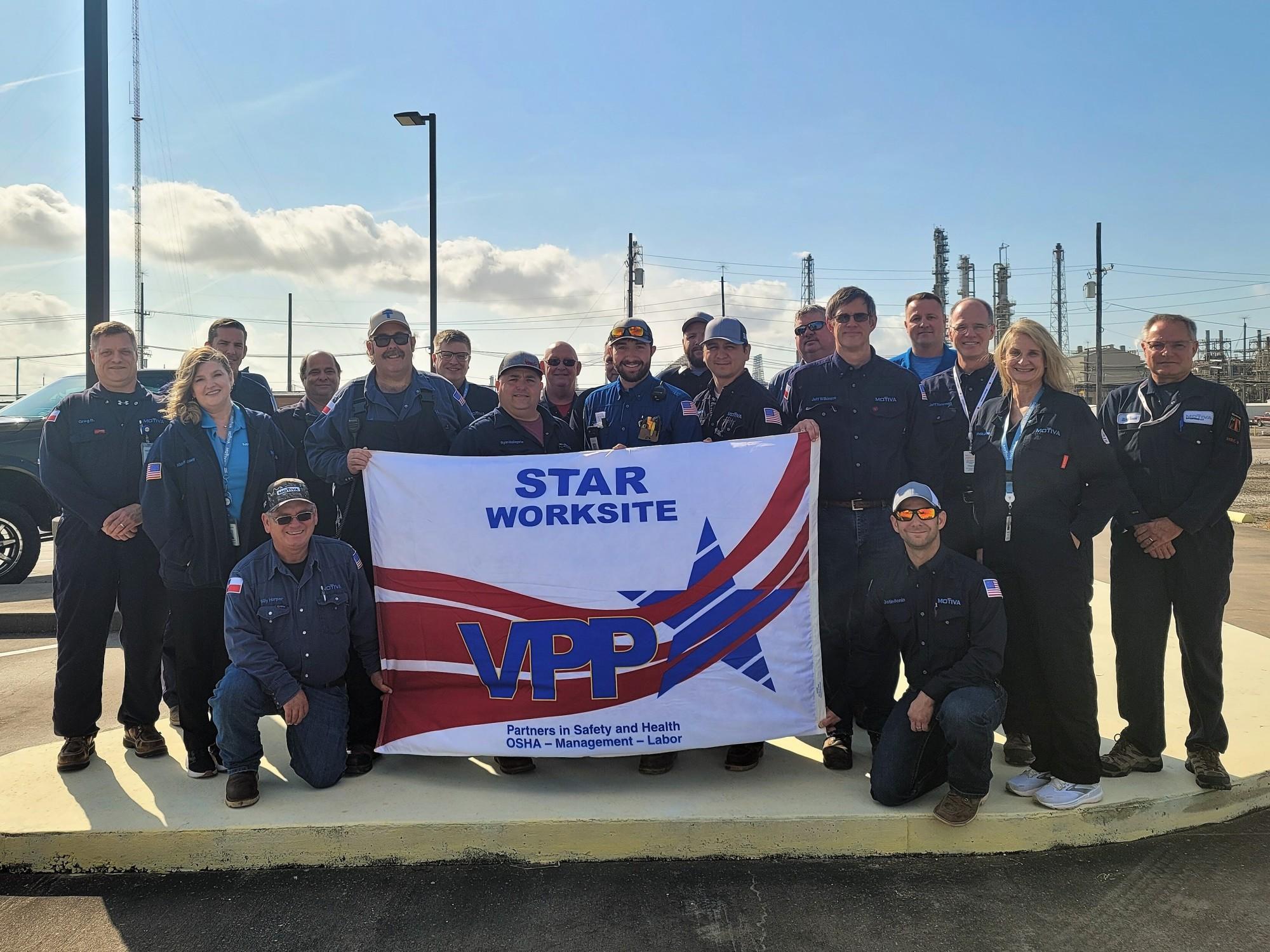 A group of Chemicals employees holding a VPP Star Worksite flag