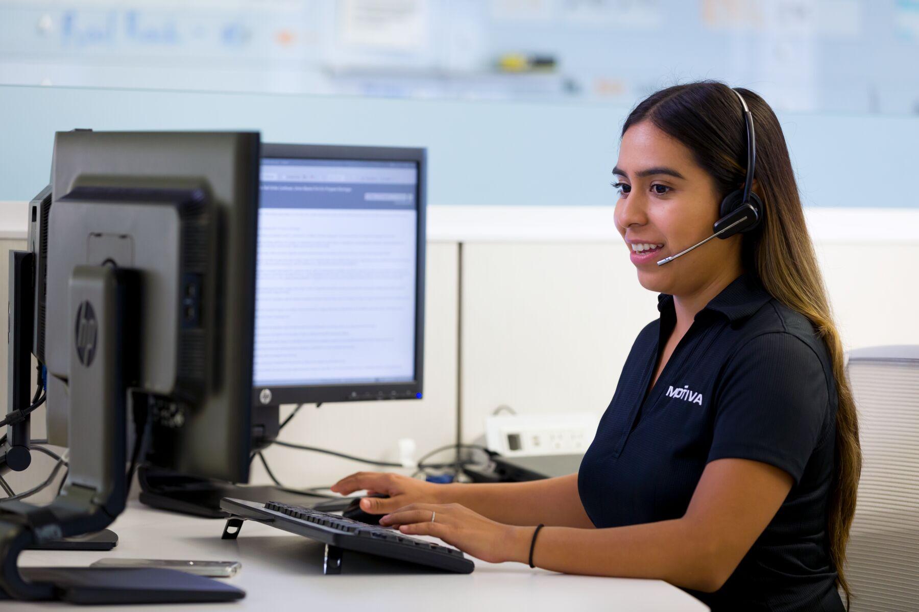 A Motiva employee talks into a headset while on a computer.