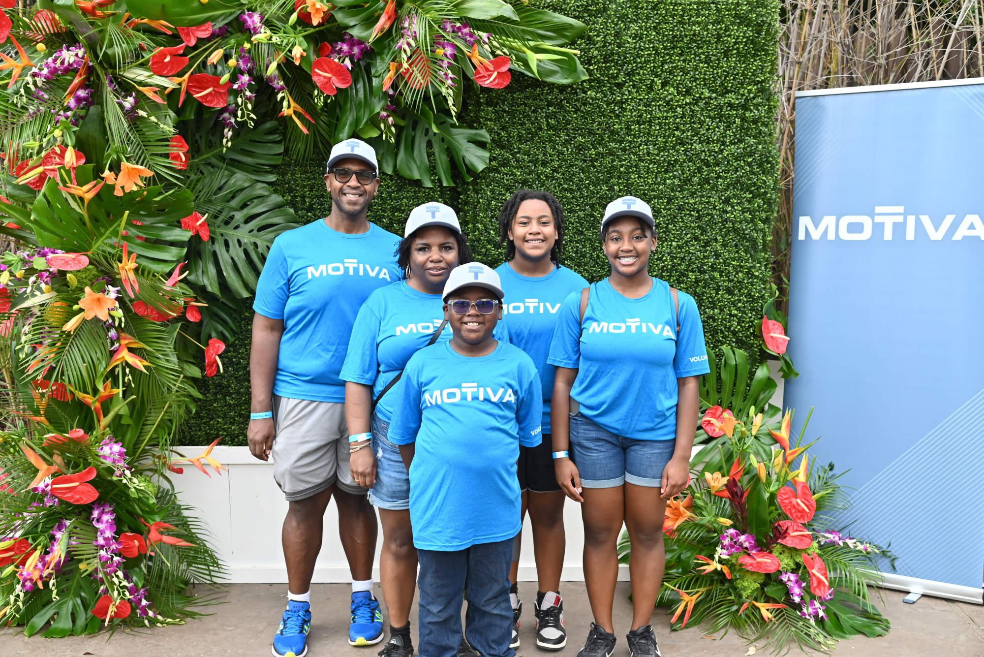 A family stands in front of a green floral backdrop.