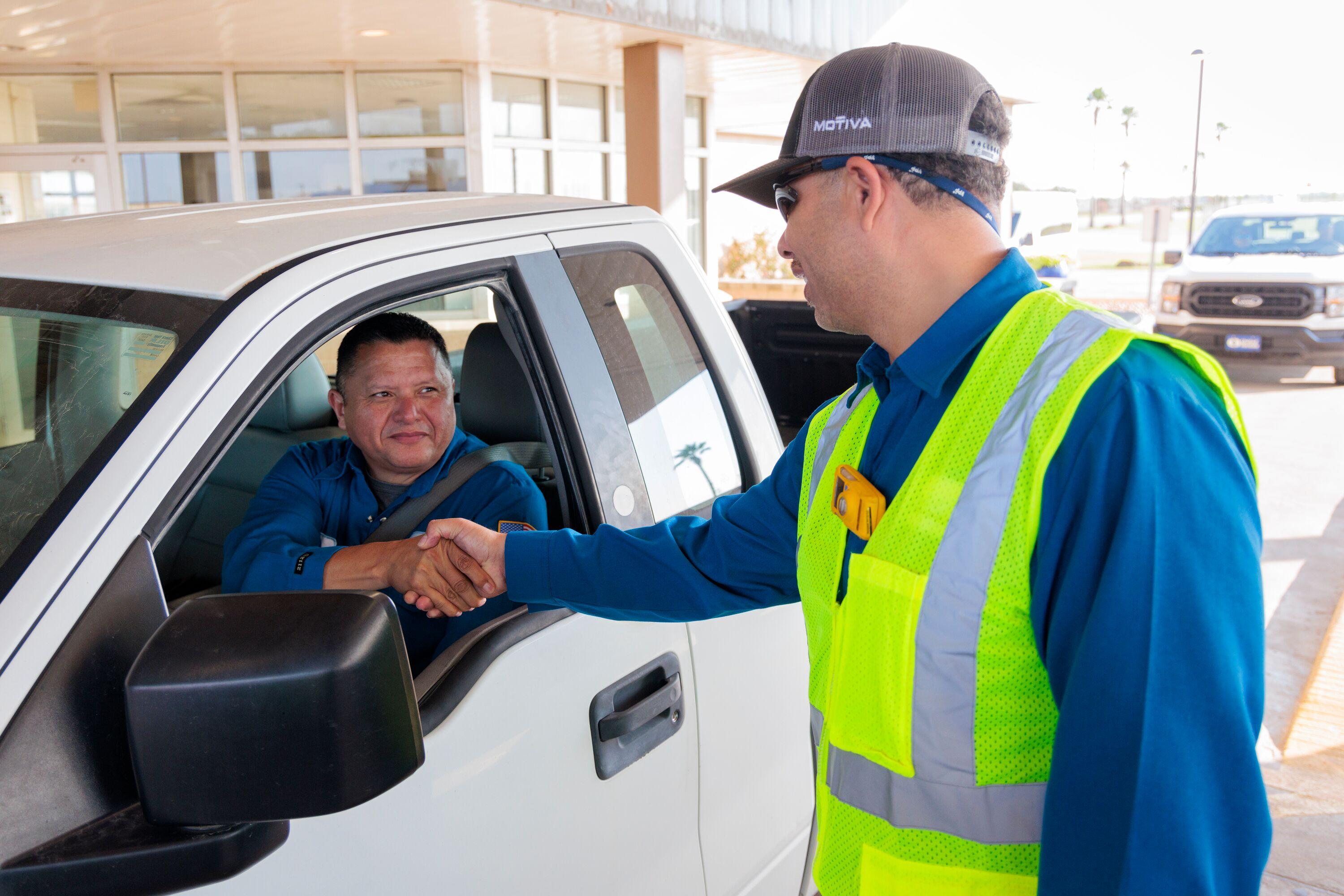 Motiva employee shaking hand of employee in car.