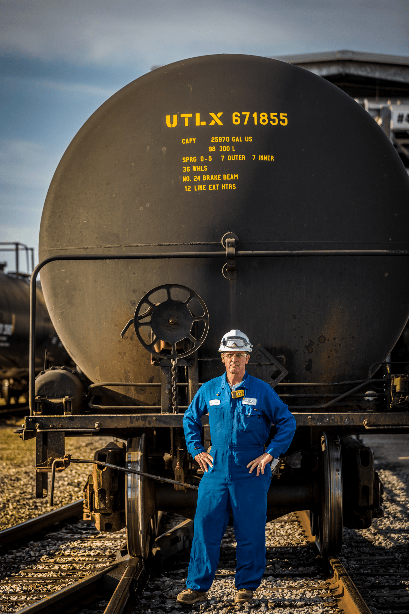 A Motiva employee stands in front of a base oils train.